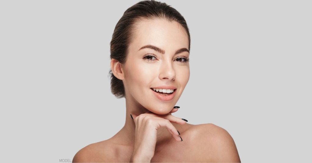 Woman smiling with her hand under her chin. (MODEL)